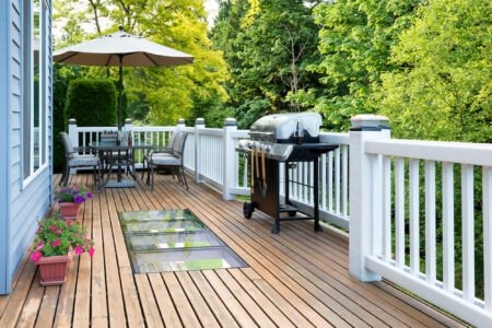 outdoor wood and glass deck with a grill and patio set