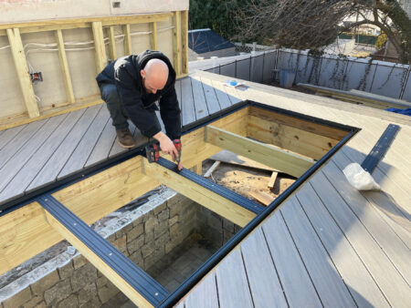 A deck builder installing a modular glass deck system called Skyfloor.