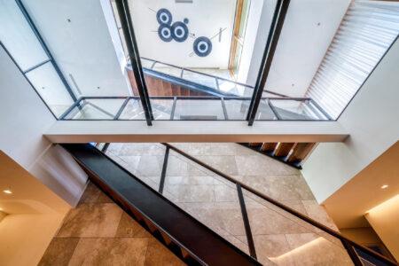 angle looking up from the ground floor at a modern home with glass flooring above