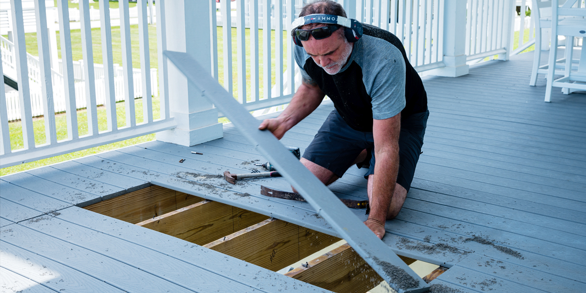 man doing deck renovation on a wooden deck replacing boards